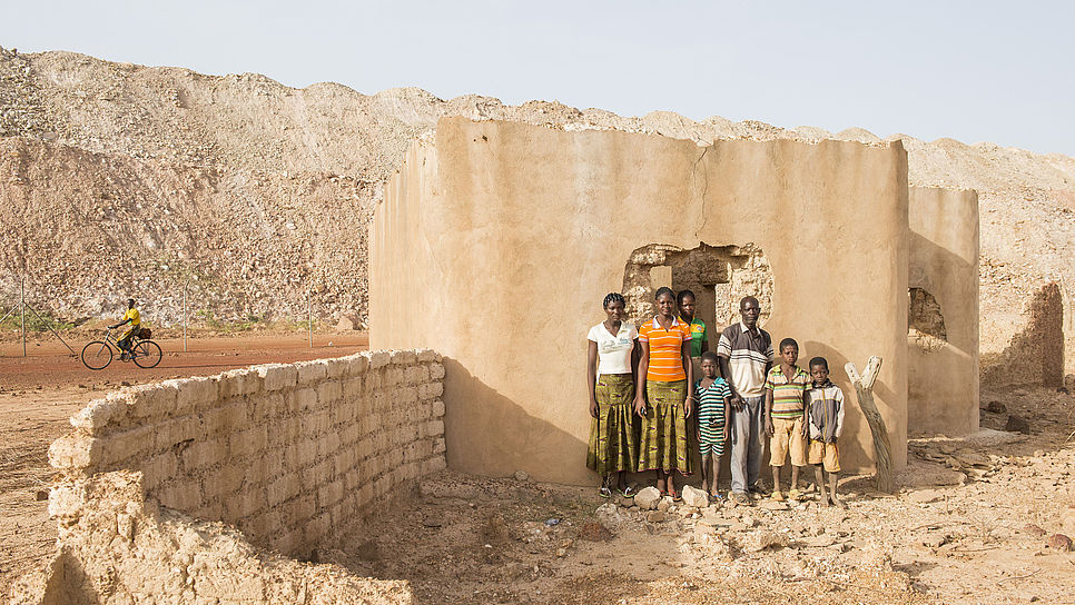 Eine Familie in Burkina Faso steht vor ihrem zerstörten Haus: Wegen dem Bau der Bissa-Goldmine wurde das ganze Dorf umgesiedelt