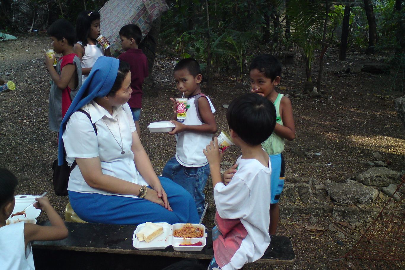 Eine Nonne schaut auf essende Kinder.