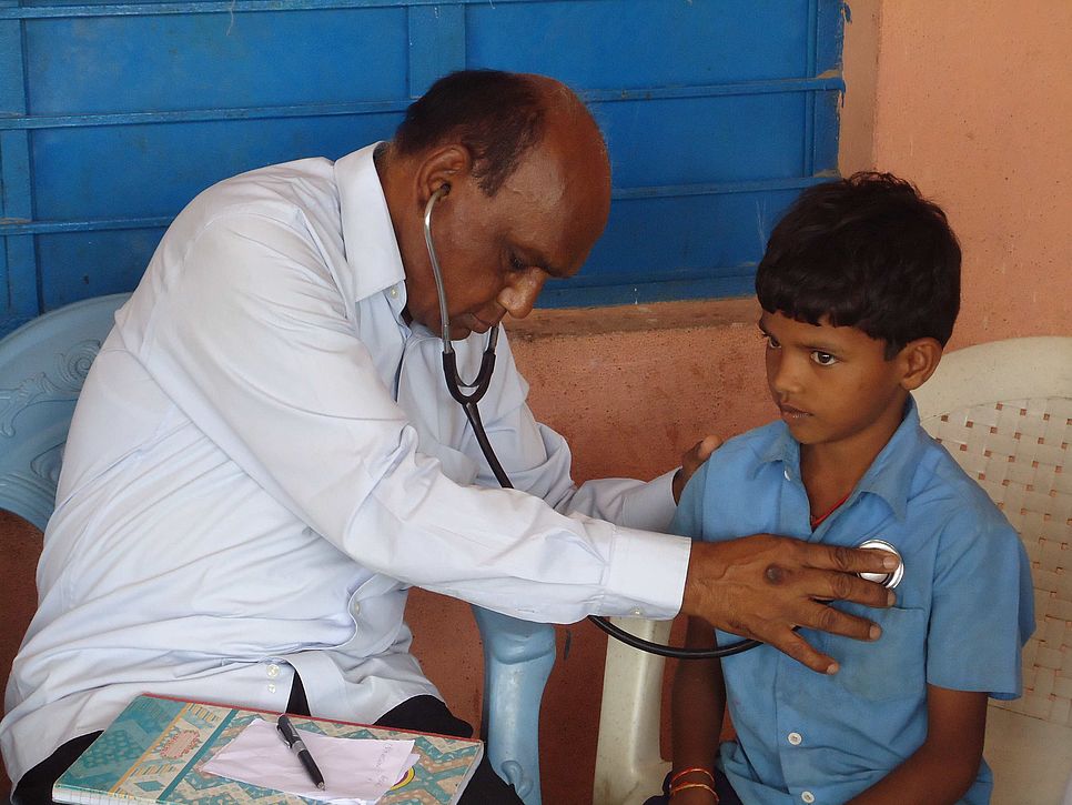 Ein Arzt hört mit einem Stethoskop einen Jungen ab