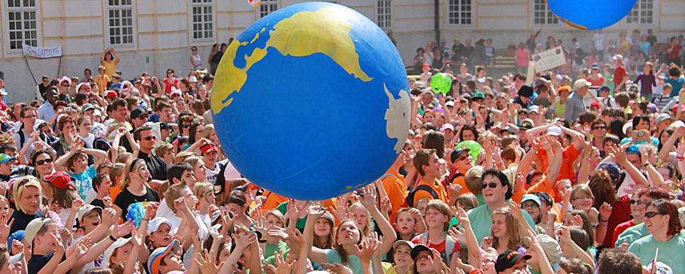 a big group of people playing with an inflatable globe