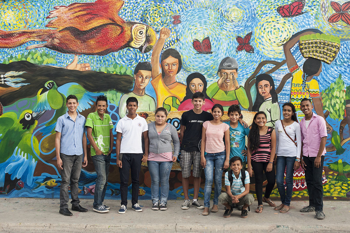Gruppe von Kindern und Jugendlichen posiert vor einem bunten Wandgemälde.
