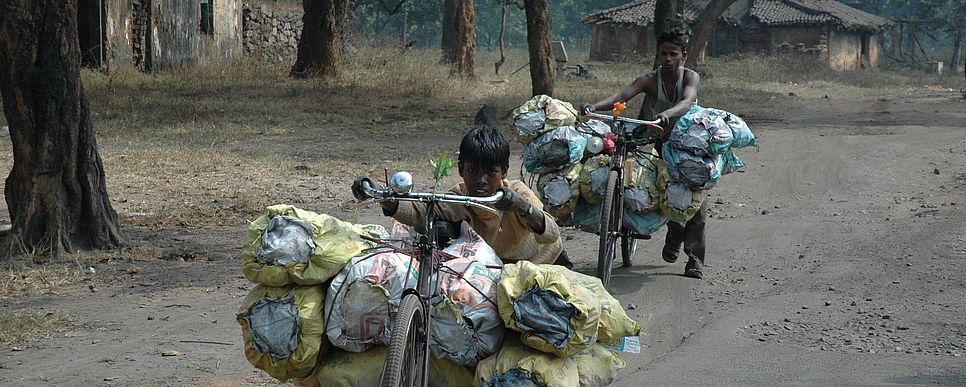 Ausbeuterische Arbeit zerstört das Leben vieler Kinder.Foto: Sanjay Kr. Mahato Zwei Buben schieben schwer beladene Fahrräder eine Straße entlang.