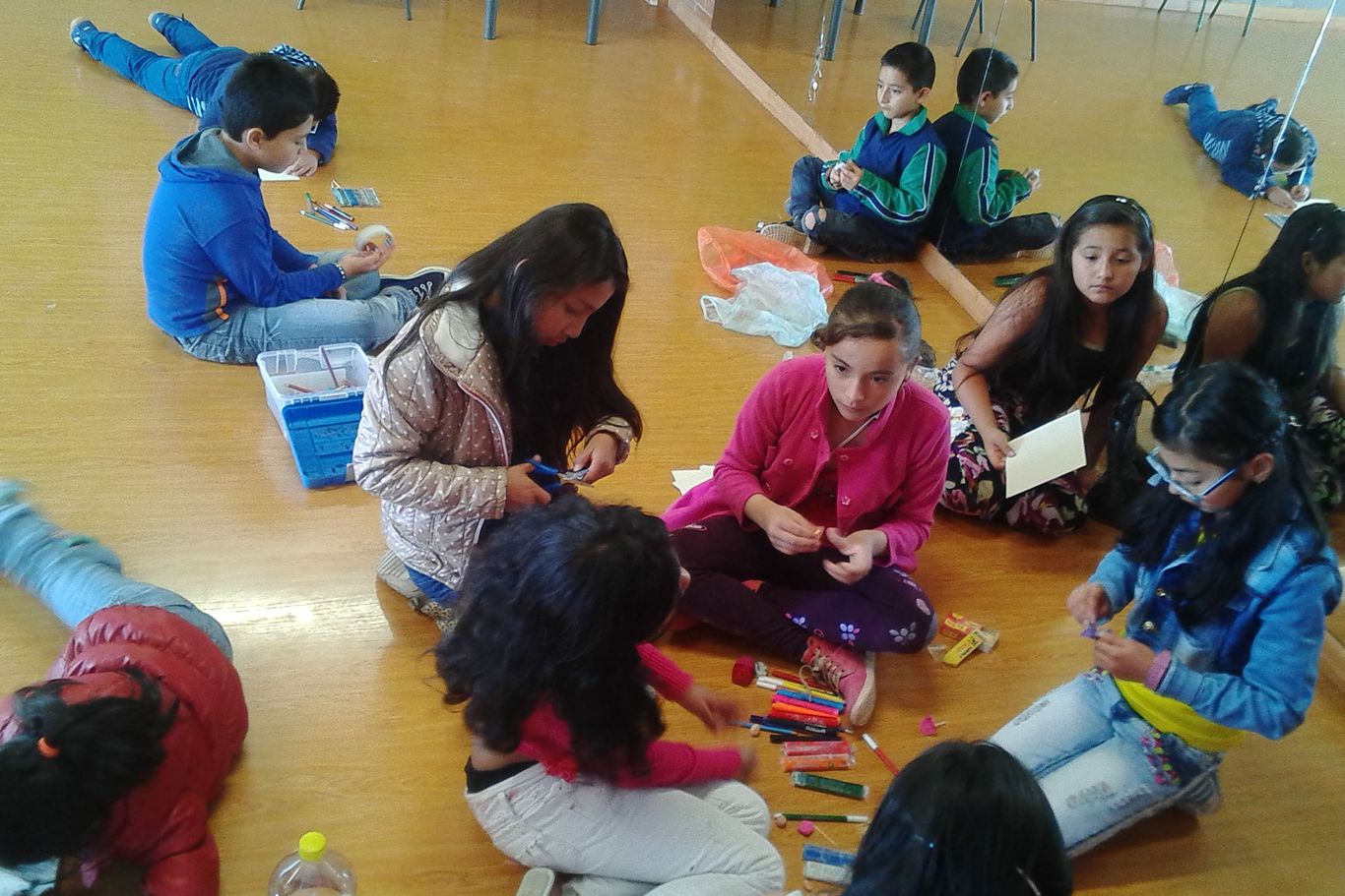 Kinder von CEPALC sitzen auf dem Boden und zeichnen und malen.