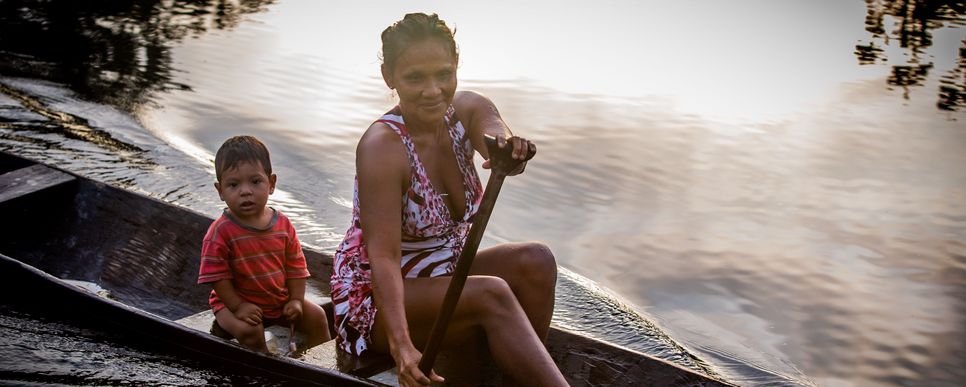 Eine Mutter fährt mit ihrem Sohn im Kanu auf dem Amazonas