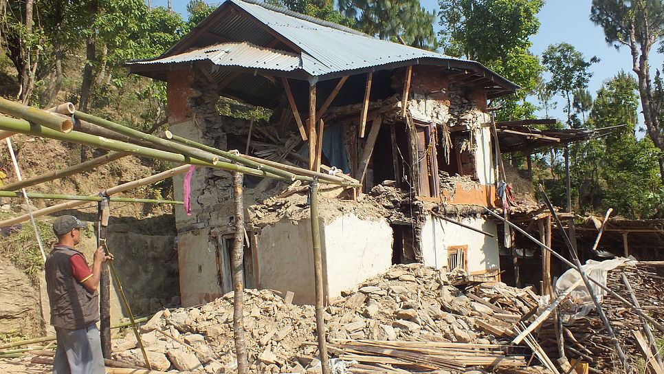 Ein Mann steht vor einem durch das Erdbeben zerstörten Haus