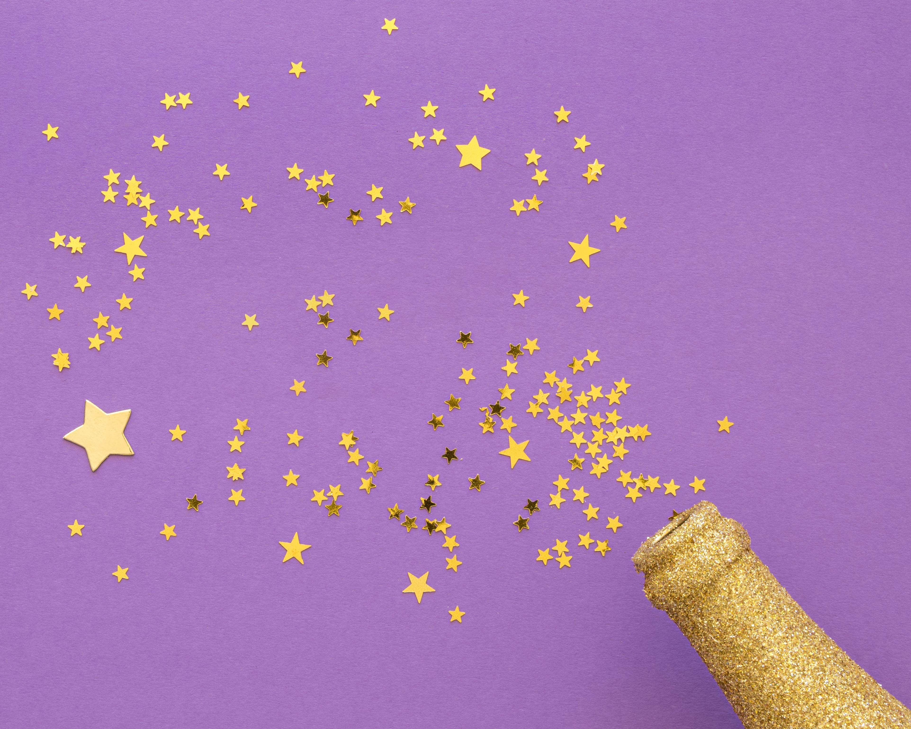 Auf einem lila Hintergrund ist eine goldene Flasche mit goldenem Stern-Konfetti zu sehen.