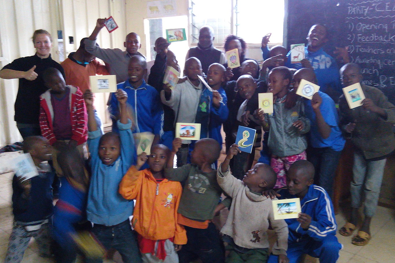 Feier zum bestandenen Schuljahr Kinder des Partnerprojekts MSDP halten Bilder in die Kamera.