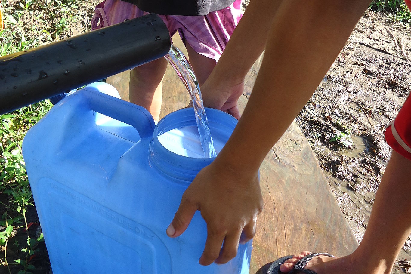 Ein blauer Kanister wird mit klaren Wasser befüllt.