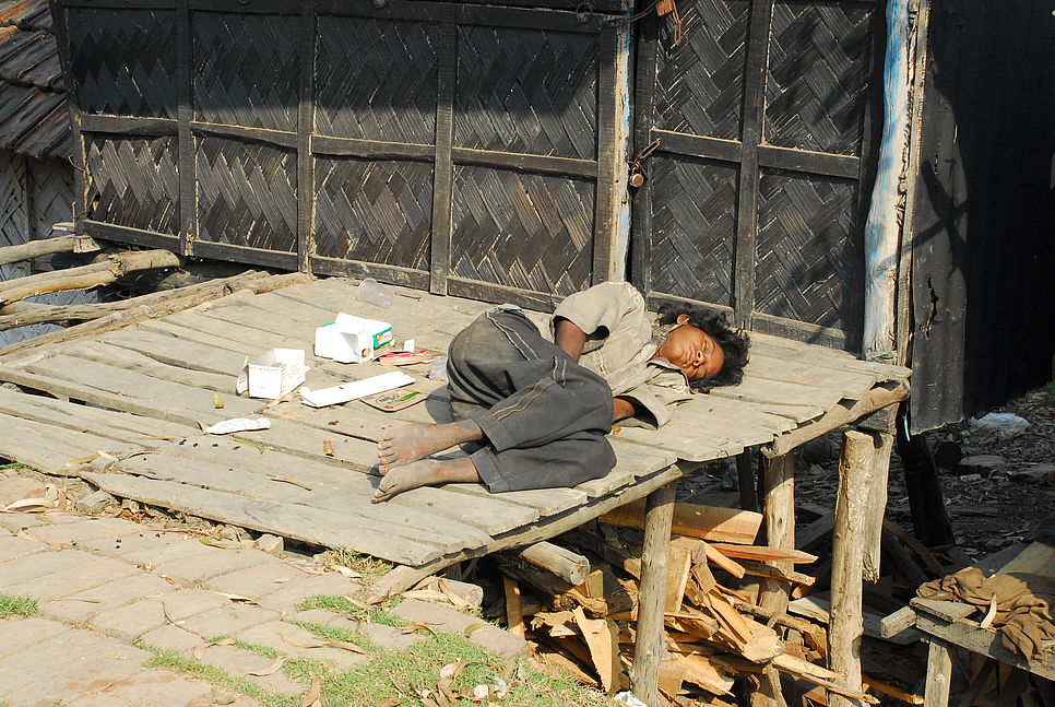 Ein Jugendlicher schläft auf einem Holzboden im Freien.
