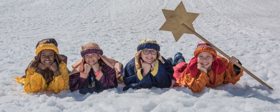 Vier Sternsinger/innen liegen im Schnee