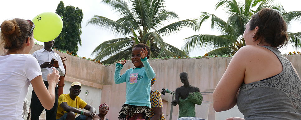 Spiel und Spaß beim LernEinsatz in Ghana, Foto: Poltschak ein Kind spiel gemeinsam mit zwei Lerneinsatzteilnehmerinnen mit einem gelben Luftballon
