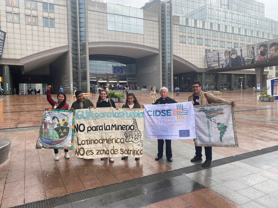 Das Bild zeigt sechs Personen, die gemeinsam Banner mit Botschaften zu Menschenrechten und Bergbauprojekten halten.