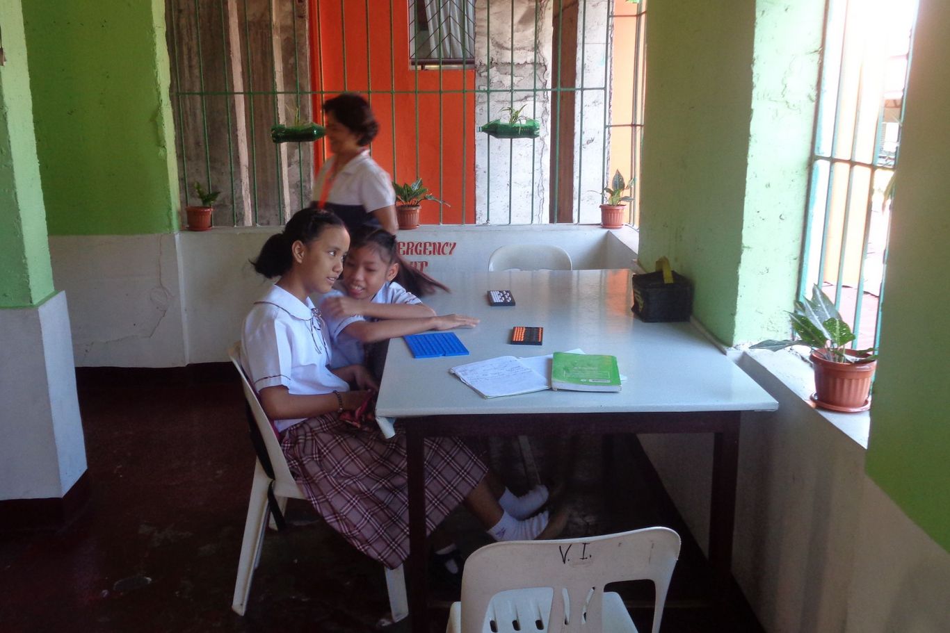 Zwei Mädchen von SPCC sitzen mit Taschenrechnern am Tisch und lernen