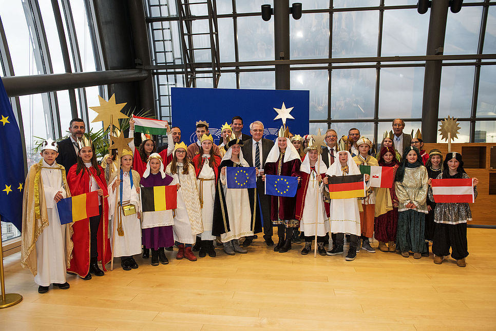 Viele Sternsingerkinder aus verschiedenen Ländern mit ihren Länderflaggen in der Hand stehen im Europaparlament.