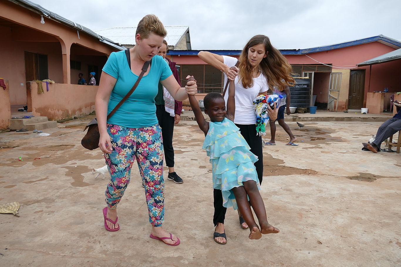 Foto: Sebastian Poltschak Zwei Teilnehmerinnen heben ein lachendes ghanaisches Mädchen an deren Händen und lassen es nach vorne schwingen.