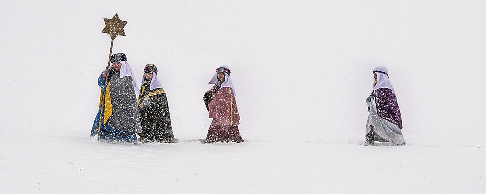 Vier Sternsingerkinder sind im Schneegestöber unterwegs.