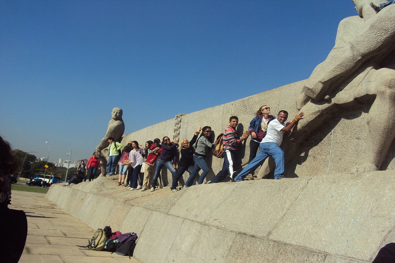 Eine Gruppe versucht scherzhaft, die Statue eines Denkmals anzuschieben.
