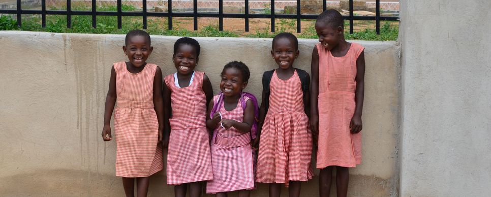 Gruppe von Schulkindern steht an einer Mauer.