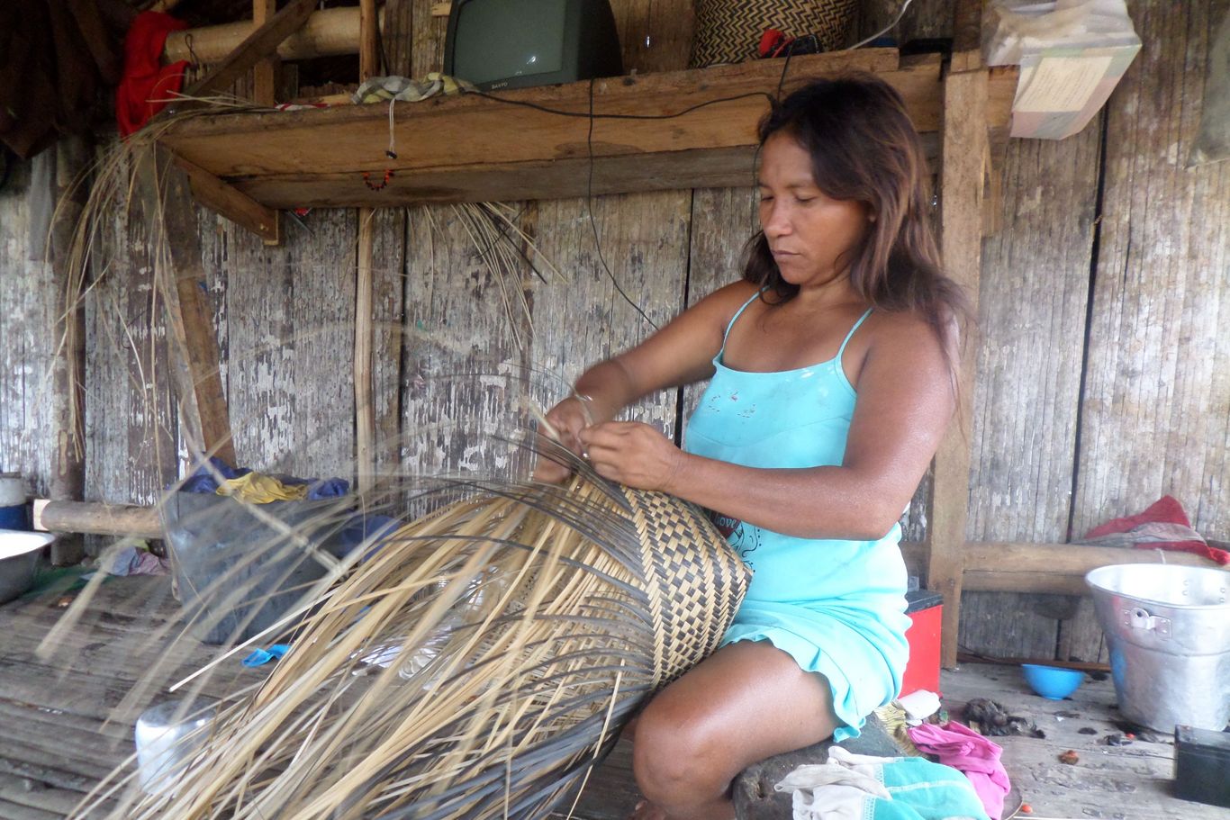 Eine indigene Frau flechtet einen Korb