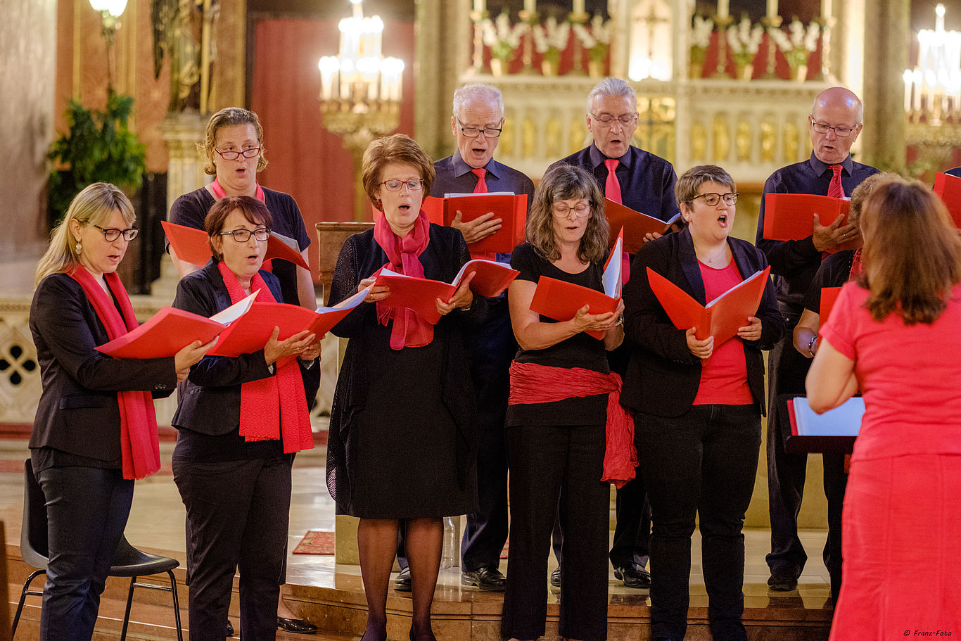 Der Chor „Vielstimmig“ der Pfarre Altlerchenfeld (Wien) singt für Bauernfamilien in Brasilien. Foto: Peleska Mehrere Personen in schwarz-roter Kleidung singen gemeinsam als Chor.
