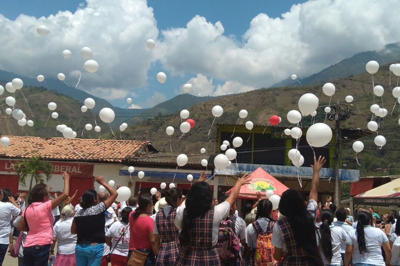 Ein Zeichen für Frieden und Versöhnung Viele Menschen stehen vor einer Häuserreihe und lassen weiße Luftballons steigen