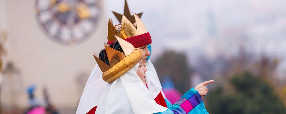 Zwei Kinder mit goldenen Kronen schauen von einer Aussichtsplattform aus auf die Stadt herab.