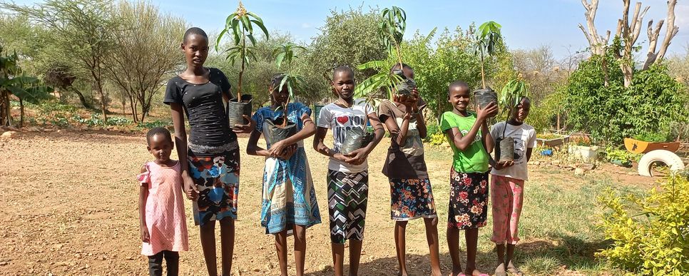 Kenianische Kinder und Jugendliche halten neue Pflanzen in ihren Töpfen in die Kamera.