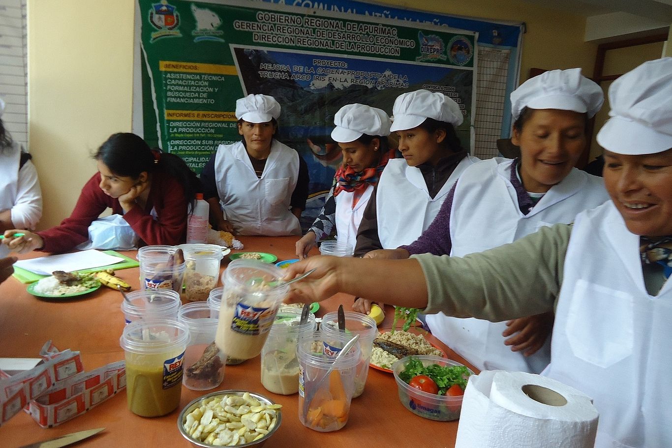 Frauen in weißen Kitteln stehen an einem Tisch von IDMA und lernen mehr über ausgewogenen Mahlzeiten.