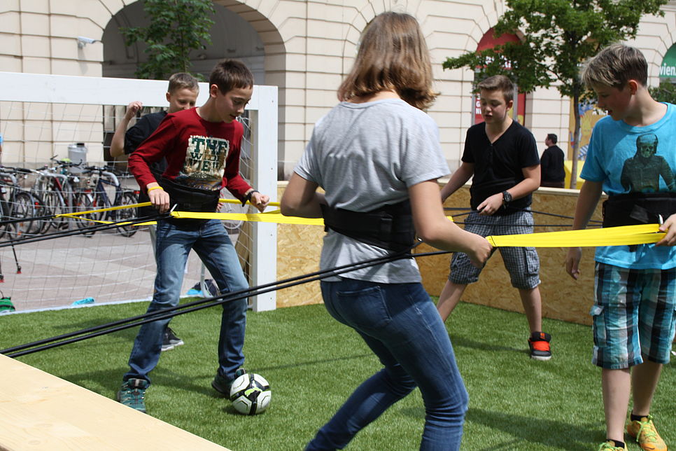 Kinder spielen mit Bändern in einem Riesenwuzzler (oder Human Kicker, Tischfußball mit Menschen)