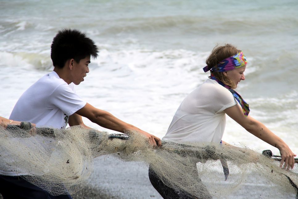 Österreicherin und Philippino ziehen gemeinsam am Fischernetz. 