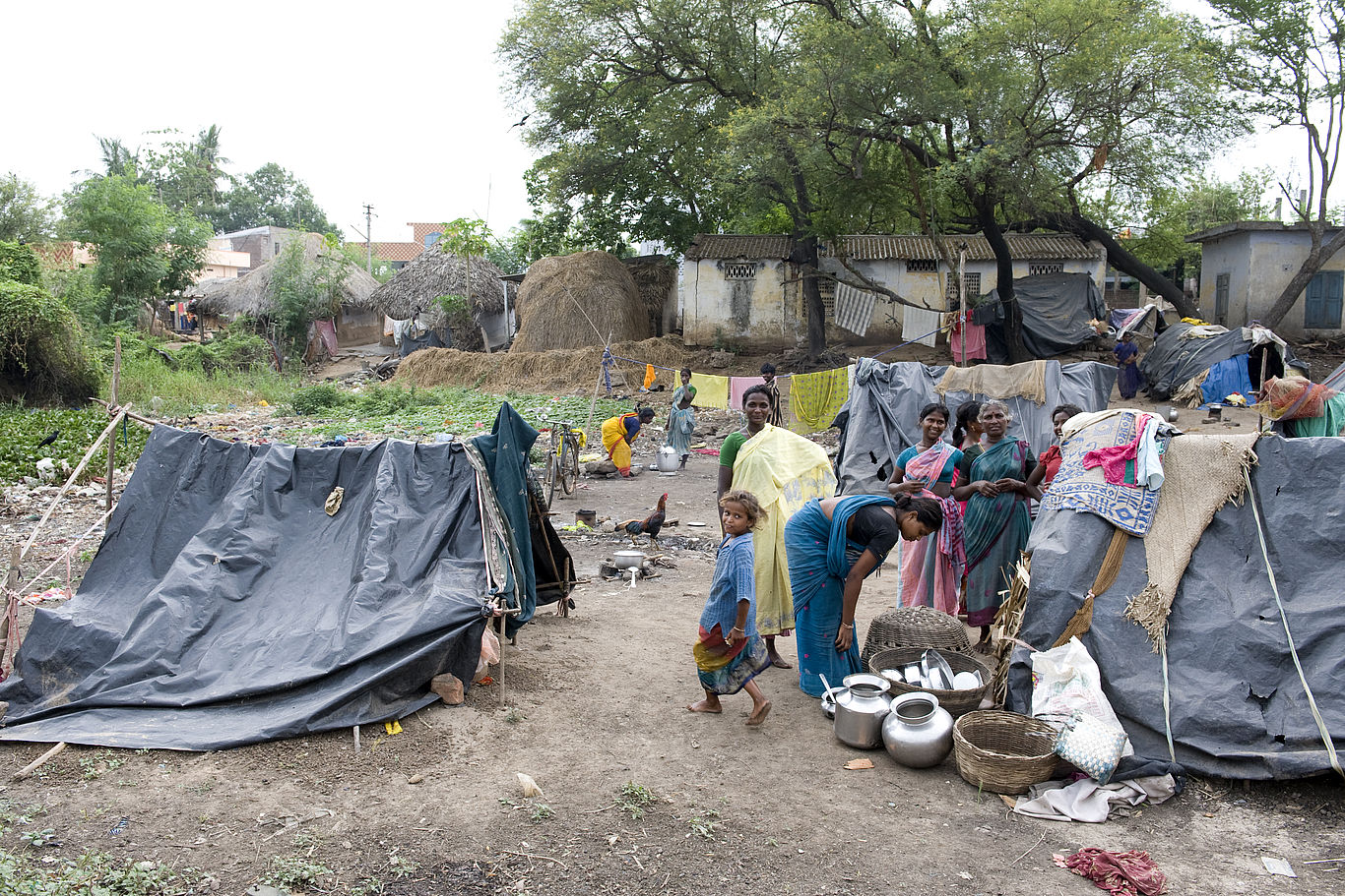 An der bitteren Armut im Slum von Vijayawada zerbrechen viele Familien. Mehrere aus schwarzen Planen konstruierte Zelte stehen auf einem Stück Land.