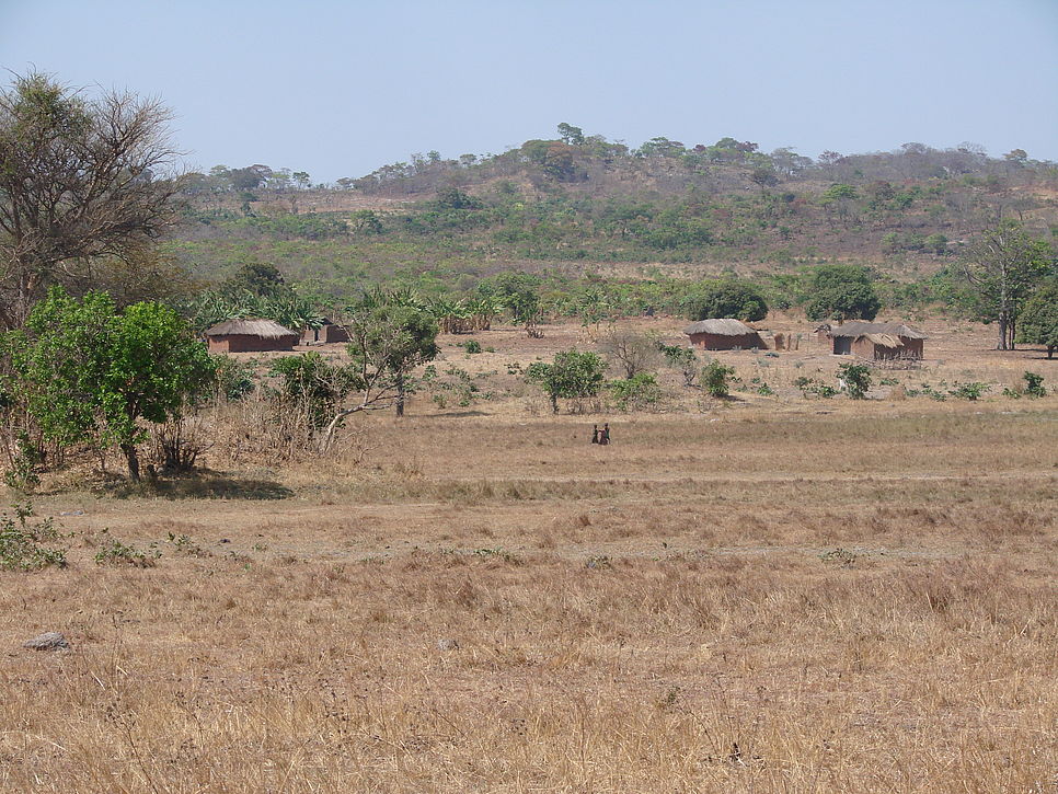 Foto zeigt ein trockenes Feld mit einigen Hütten und wenig Grünflächen.