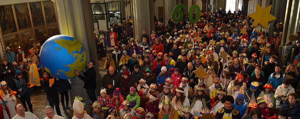 Sendungsfeier der Katholischen Jungschar der Diözese Innsbruck Viele, als Sternsinger/innen verkleidete Kinder sitzen mit ihren Familien in einer Kirche und es wird ein Weltkugel Ball hochgehalten