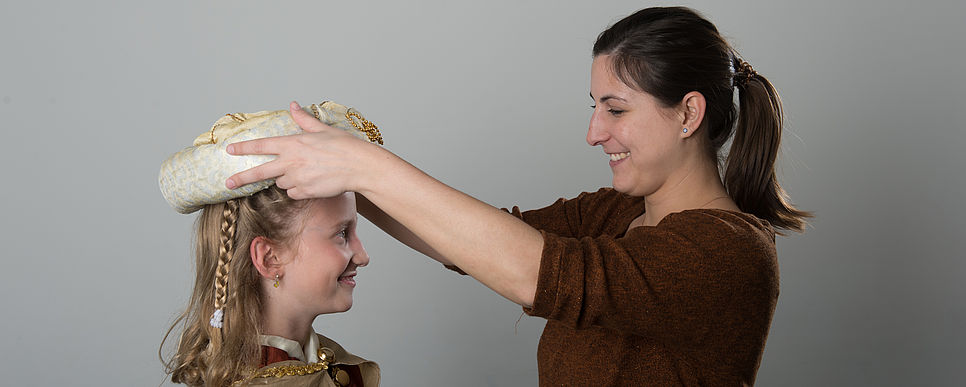 Begleitpersonen vorbereiten, Foto: Mühl Frau setzt einer Sternsingerin eine Krone auf.