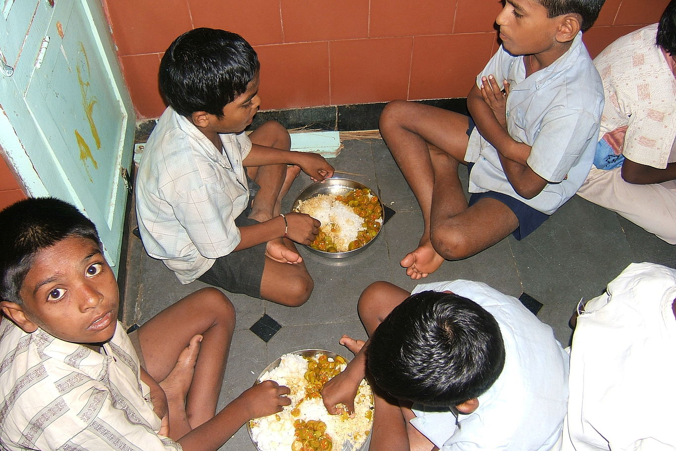 Regelmäßiges Essen und fürsorgliche Betreuung stehen am Beginn. Einige Kinder sitzen zusammen beim Essen