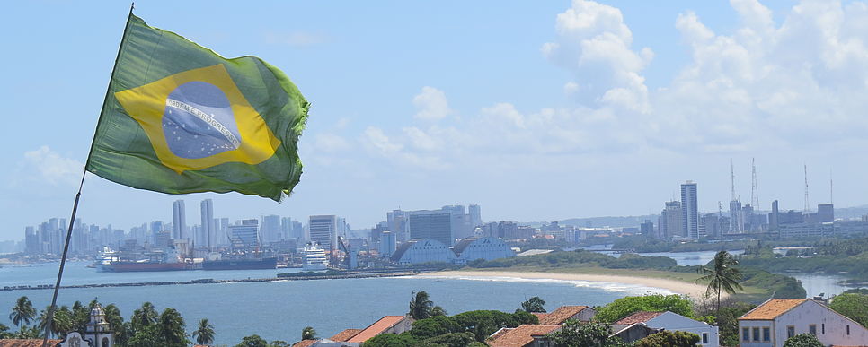 brasilianische Flagge und im Hintergrund Skyline an einer Küste