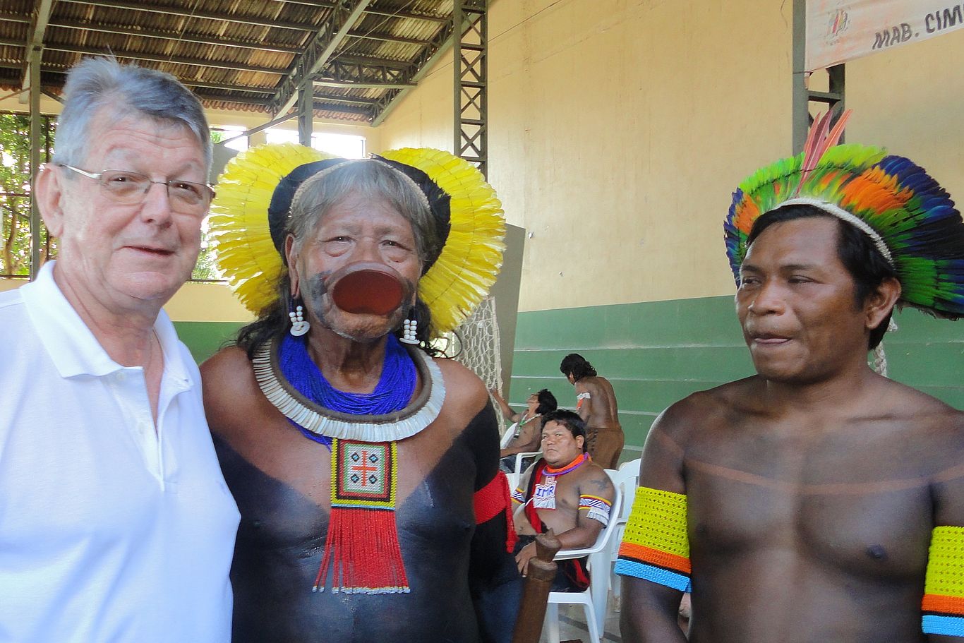 In Brasilien steht die katholische Kirche, z.B. Alt-Bischof Erwin Kräutler, den indigenen Völkern zur Seite. Foto: DKA Drei Männer, zwei davon mit Federn geschmückt, schauen in die Kamera