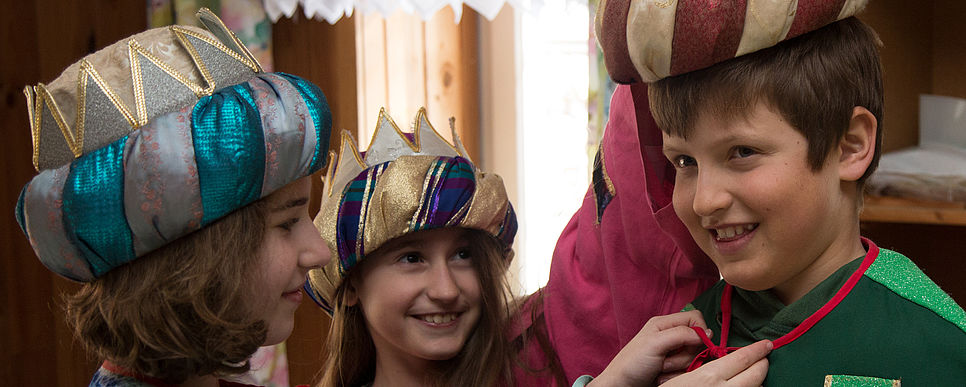 Drei Sternsinger bereiten sich auf das Sternsingen vor