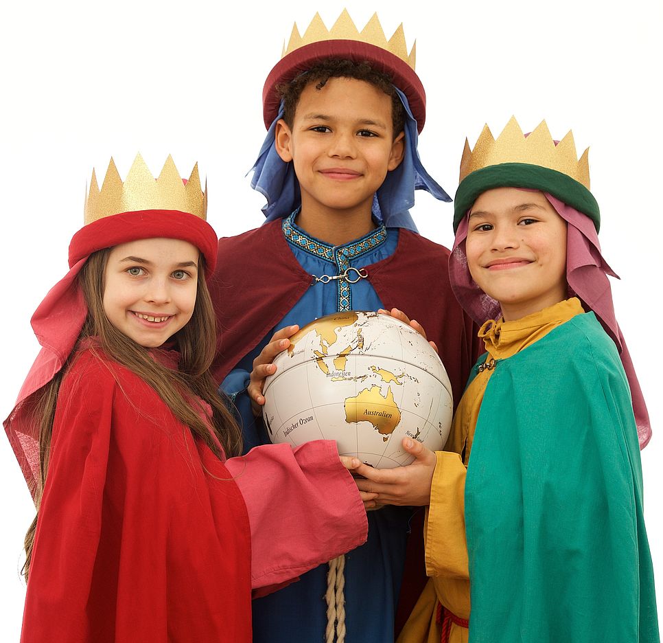 Drei Sternsingerkinder halten einen Globus.