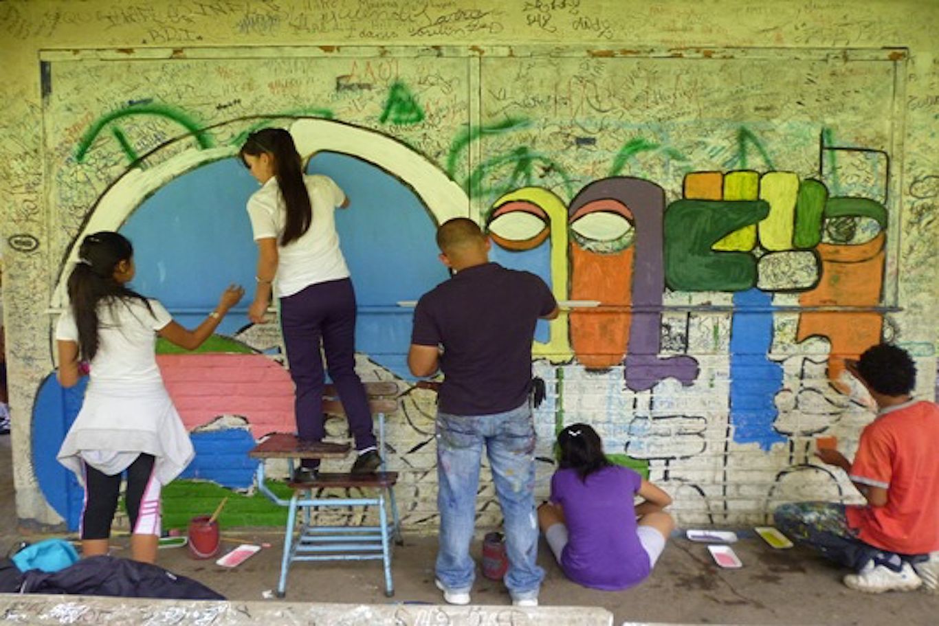 Mehrere Kinder und ein Betreuer bemalen eine Wand