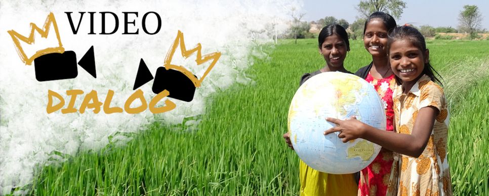 Drei Mädchen aus Indien halten eine große Weltkugel und lächeln, sie stehen in einem Feld.. Links im Bild ist das Logo zum Videodialog.