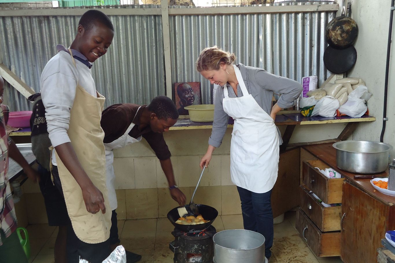 In der Küche werden Köstlichkeiten herausgebacken Jugendliche von MSDP kochen gemeinsam mit einer SolidarEinsatz Teilnehmerin auf einem Gaskocher.