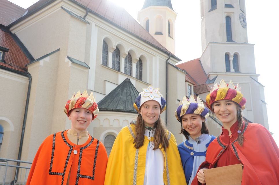 Sternsingerinnengruppe steht vor einer Kirche