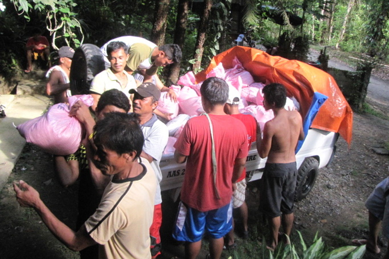 Eine Gruppe Männer verteilt rosa Plastiksäcke.