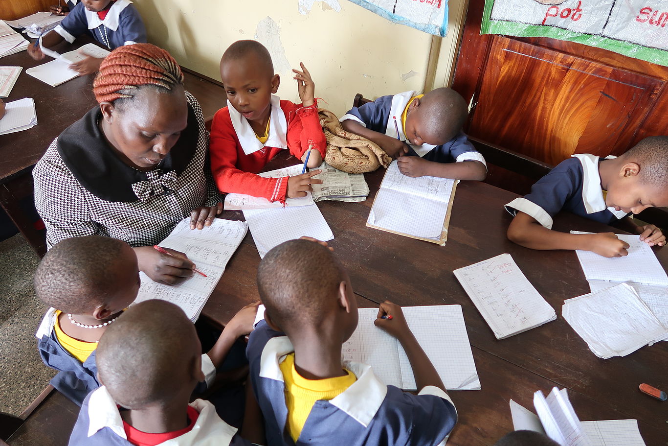 Bildung ist der Schlüssel zu einer besseren Zukunft. Foto: Seidl Lehrerin und Kinder sitzen am Tisch und lernen gemeinsam.