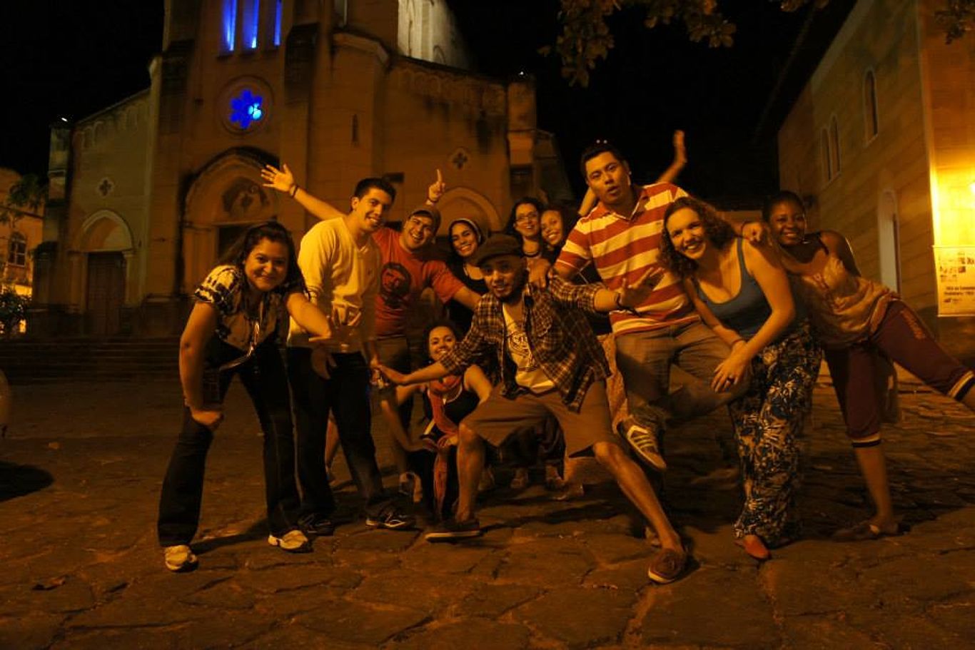 Eine Gruppe Jugendlicher und Erwachsener steht Nachts vor einer Kirche und posiert für das Foto