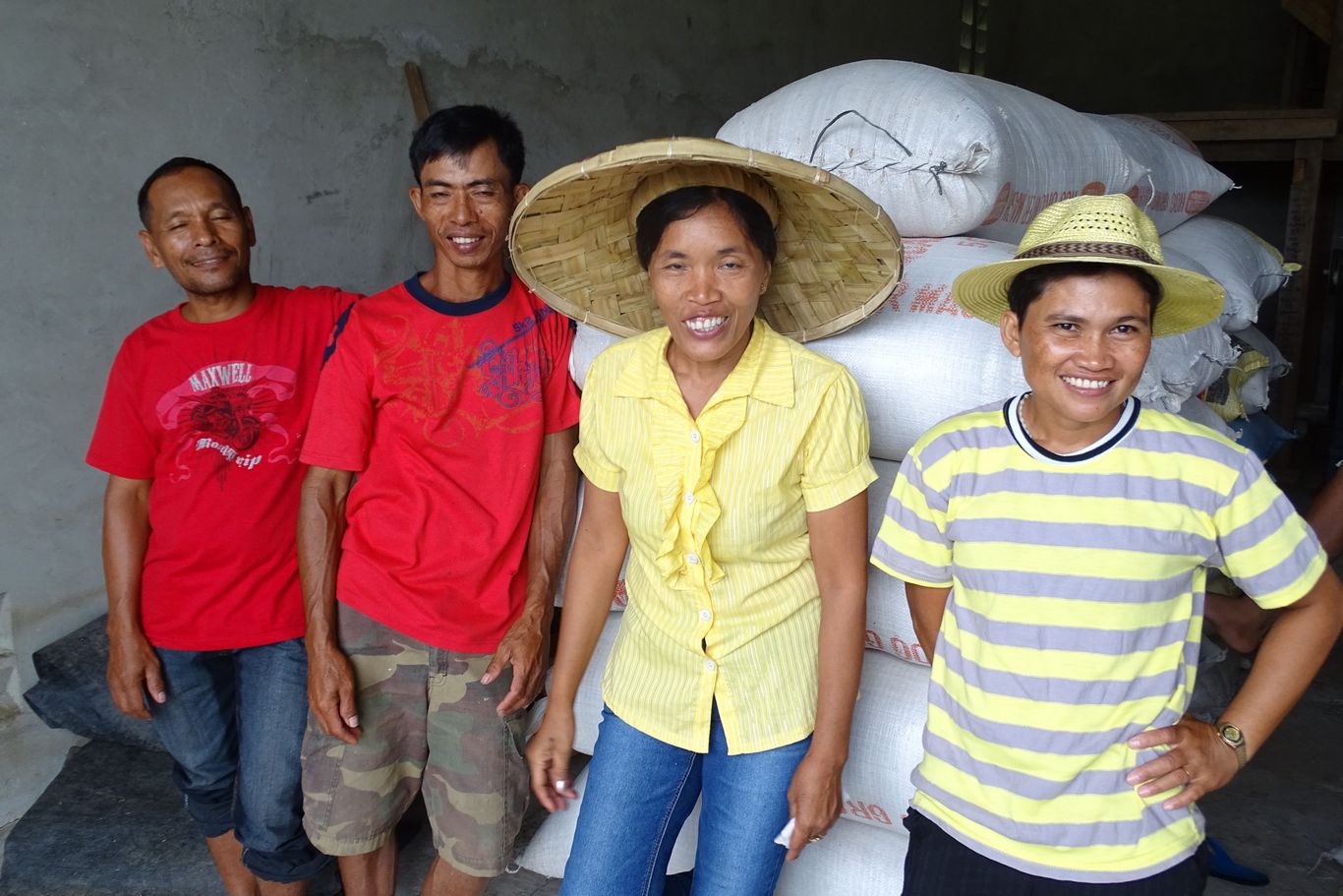 Gruppe von Bauern und Bäuerinnen vor Reissäcken