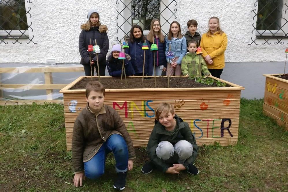 Kinder stehen und hochen vor ihrem Hochbeet in Münster