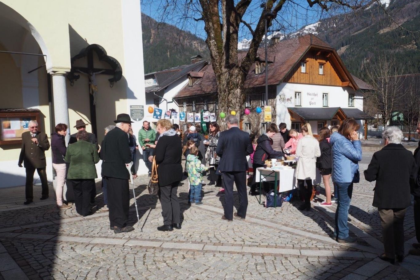 Ein Kirchenvorplatz auf dem bei kleinen Ständen viele Menschen stehen.