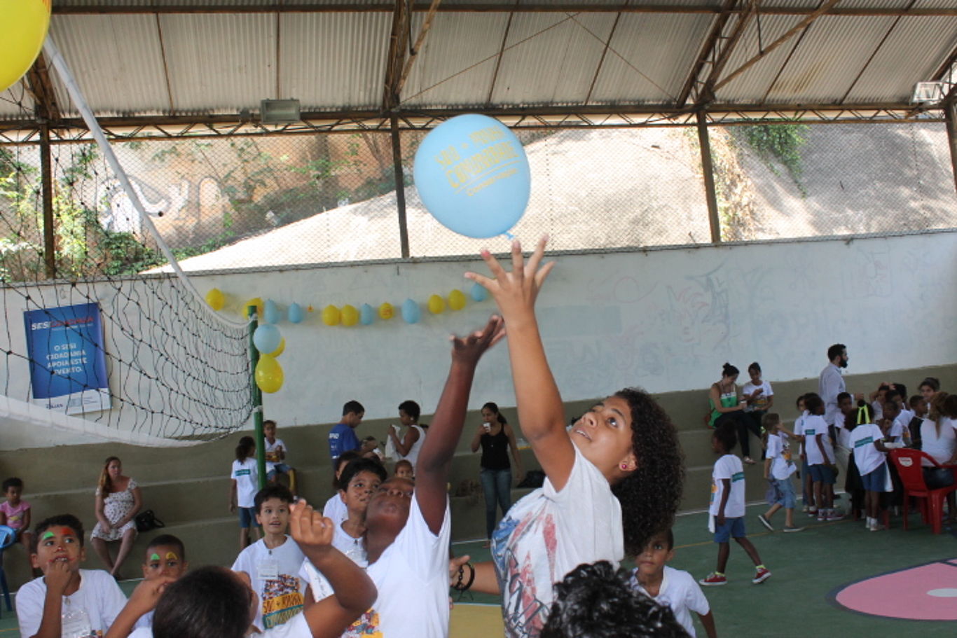 Viele Kinder spielen an einem Volleyballnetz mit einem Luftballon.